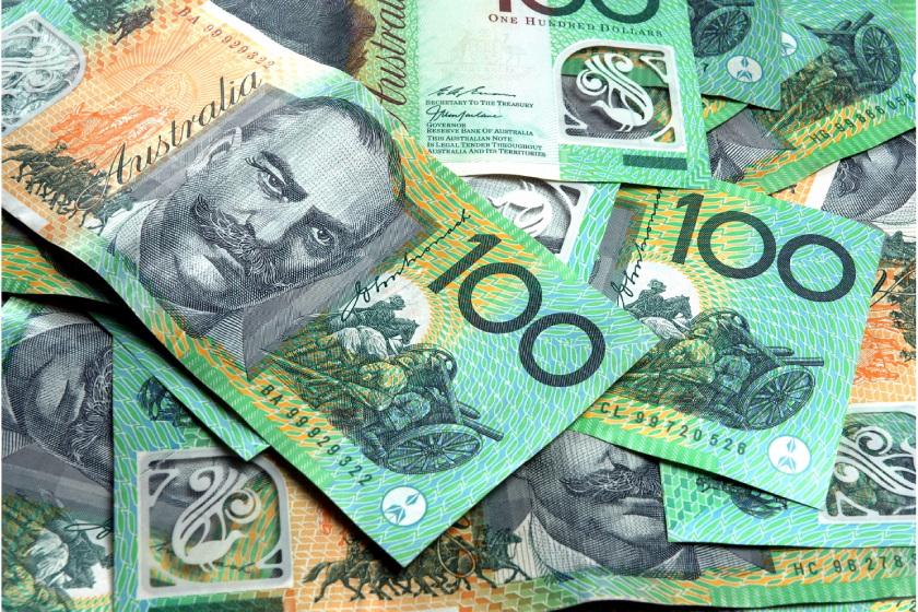 Australian 100 dollar notes stacked on top of one another in a messy way.  