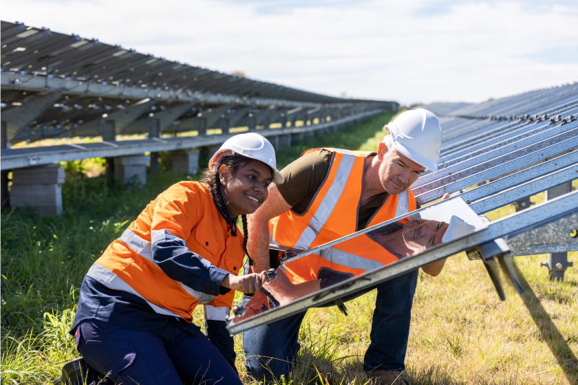 engineers working on a solar farm installation. Their experessions are happy and both are happy to be working on the same thing. 