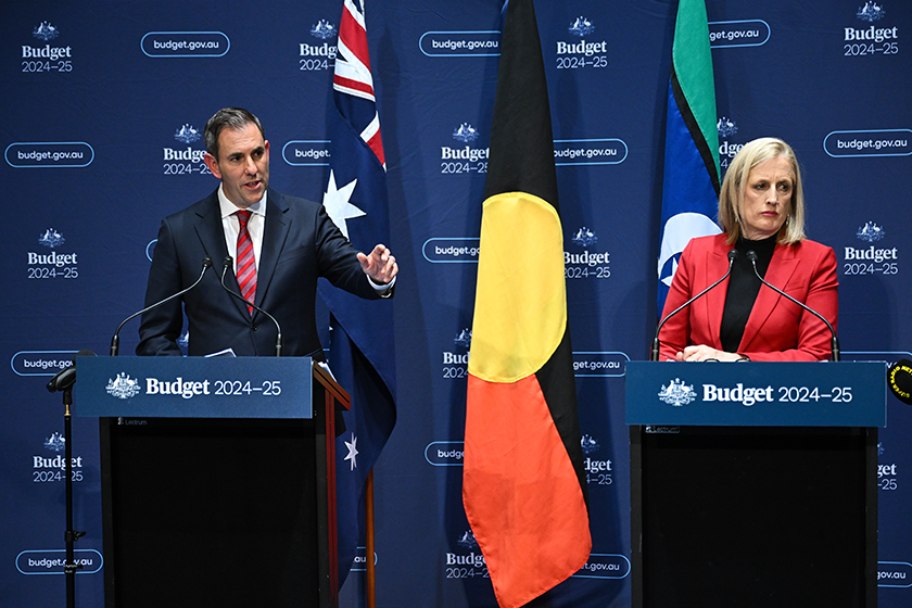 Jim Chalmers and Katy Gallagher stand at podiums in front of a Federal Budget media wall.