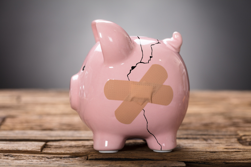 Illustration of a cracked piggybank being kept together by band aids