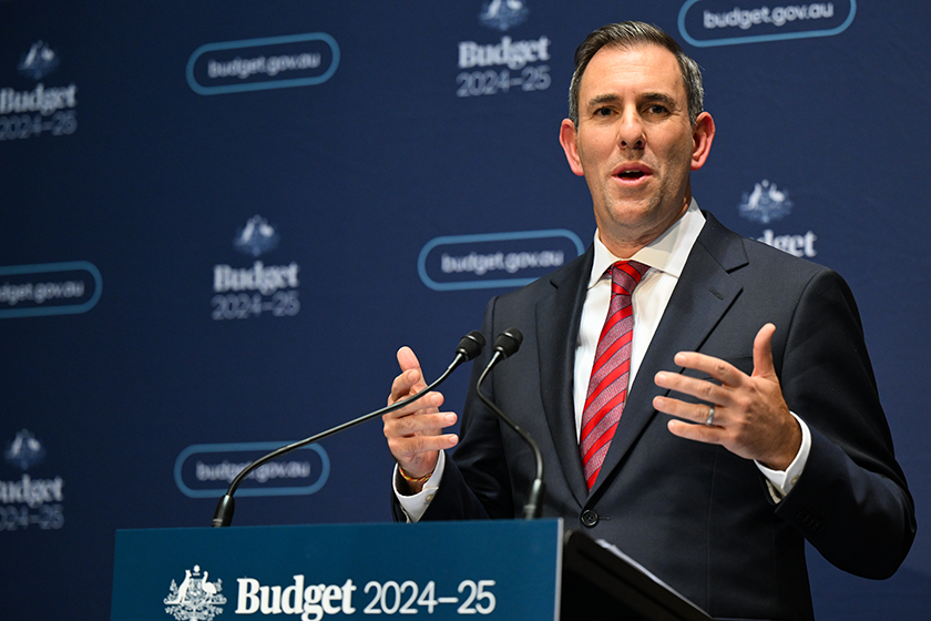 Jim Chalmers stands behind a podium decorated in Federal Budget 2024 branding, speaking